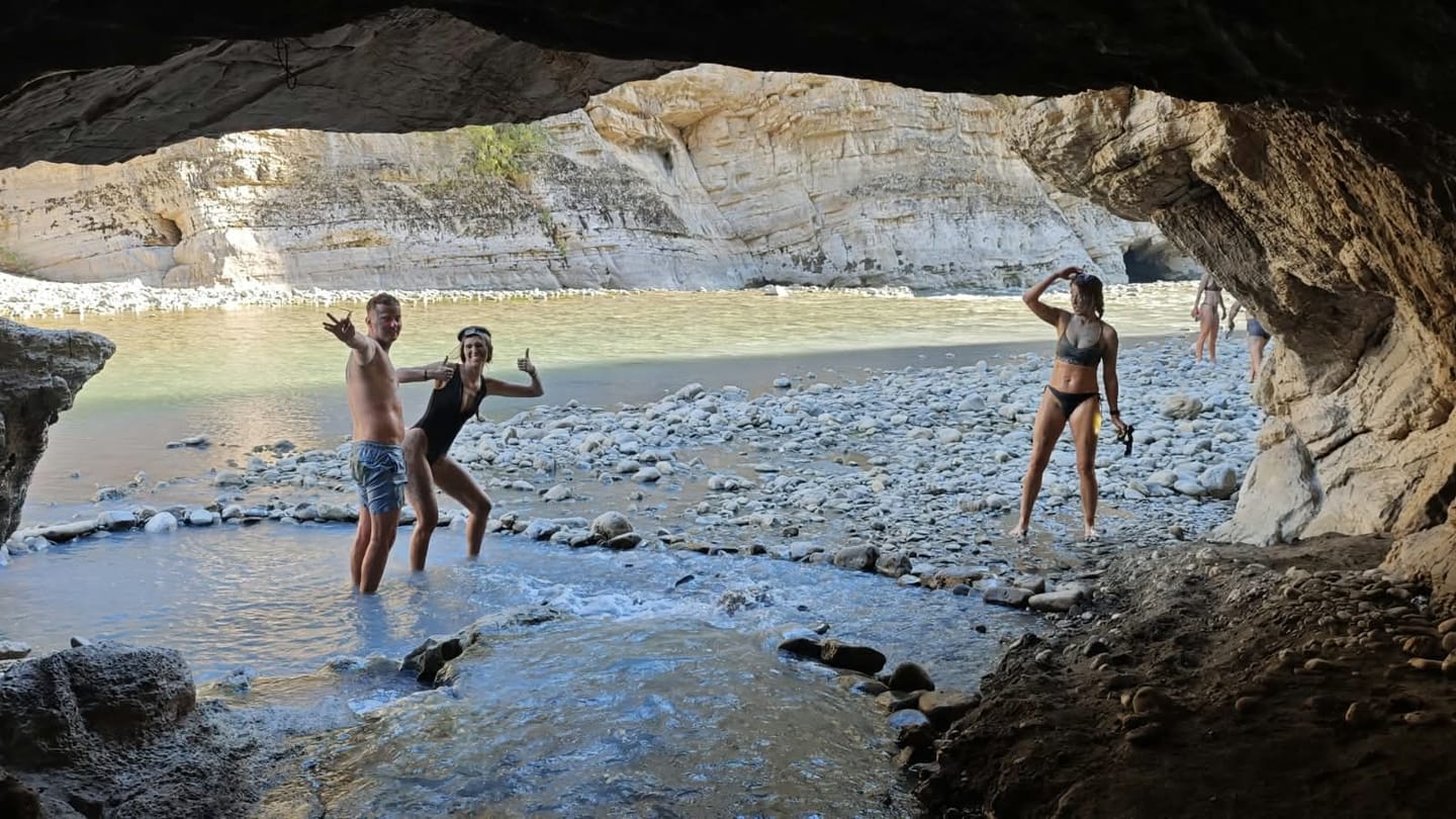 Riders splashing in the river near a cave